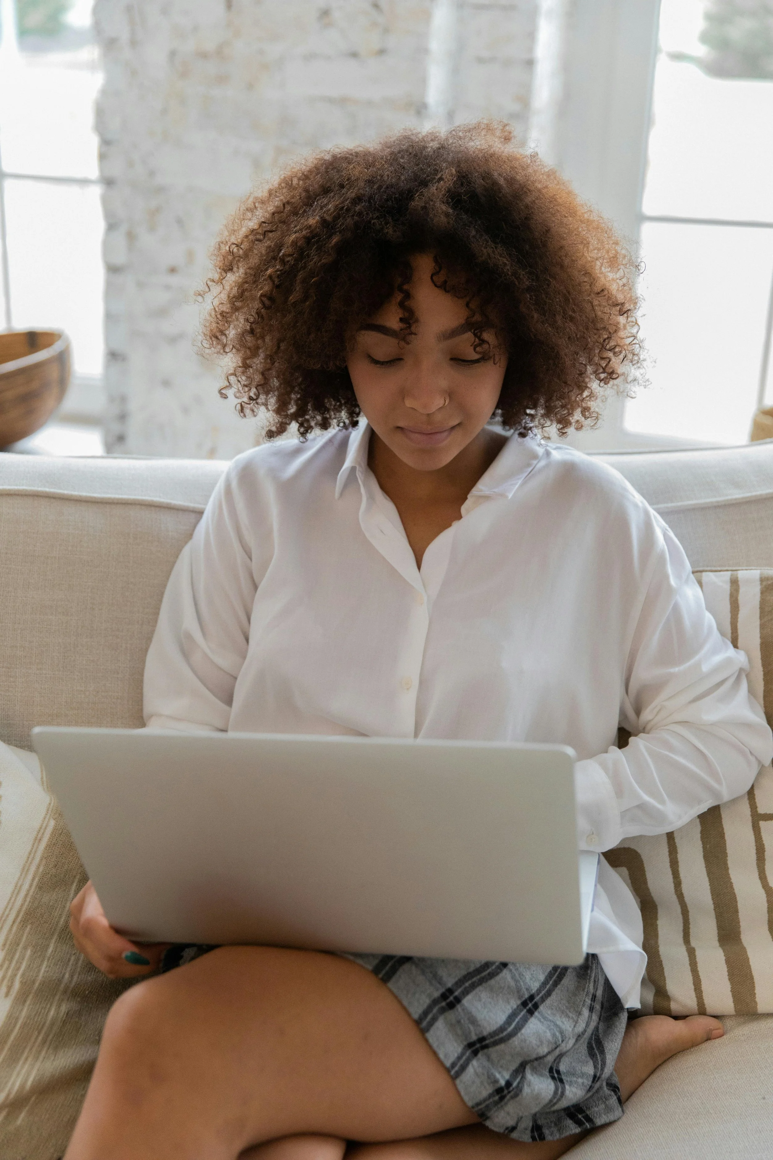 Femme assise sur un sofa qui fait des recherches à l'ordinateur