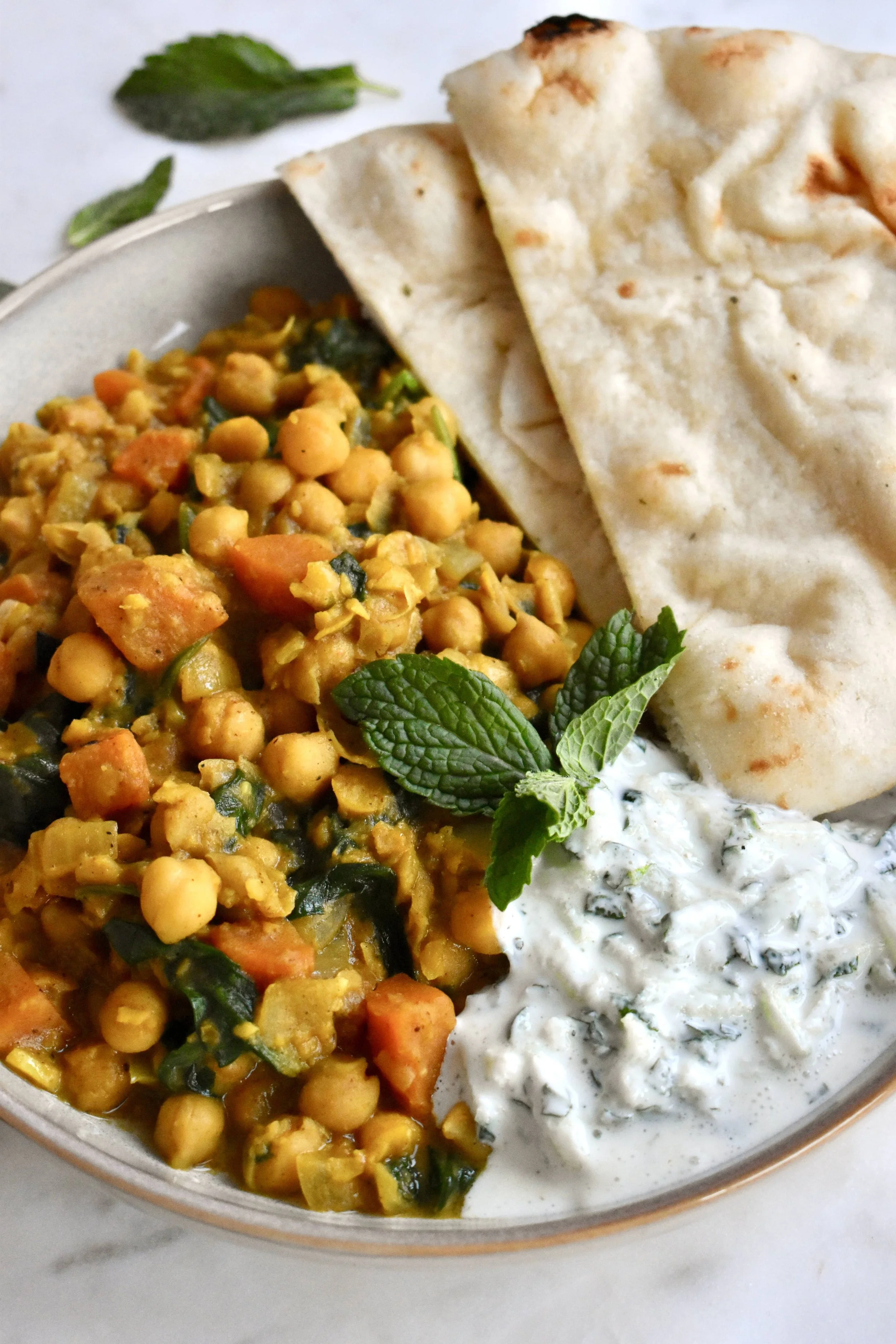 Cari de pois chiches et patate douce, servi avec sauce yogourt-concombre et pain naan