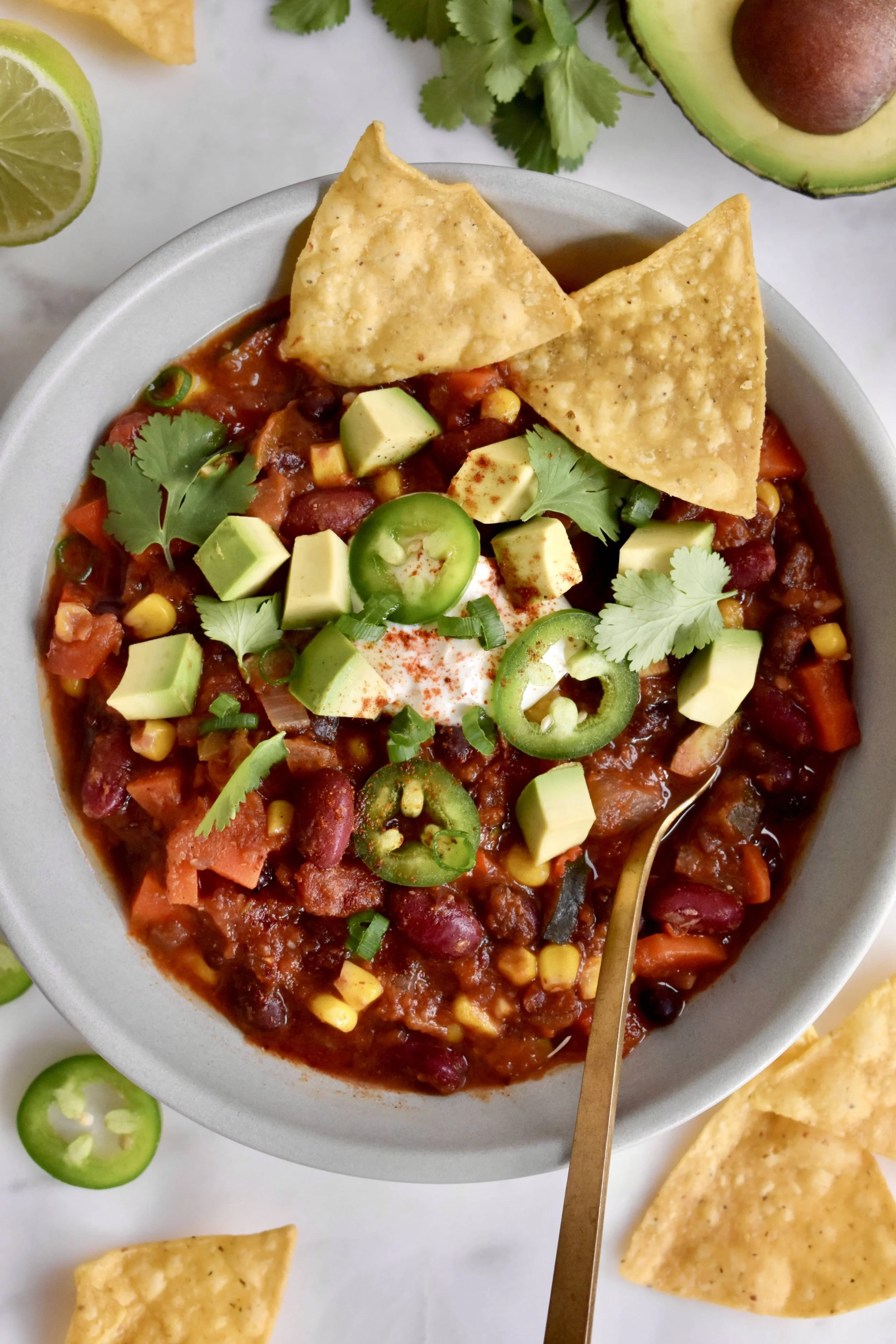 Un bol de chili végétarien avec avocat, coriandre et croustilles de maïs.
