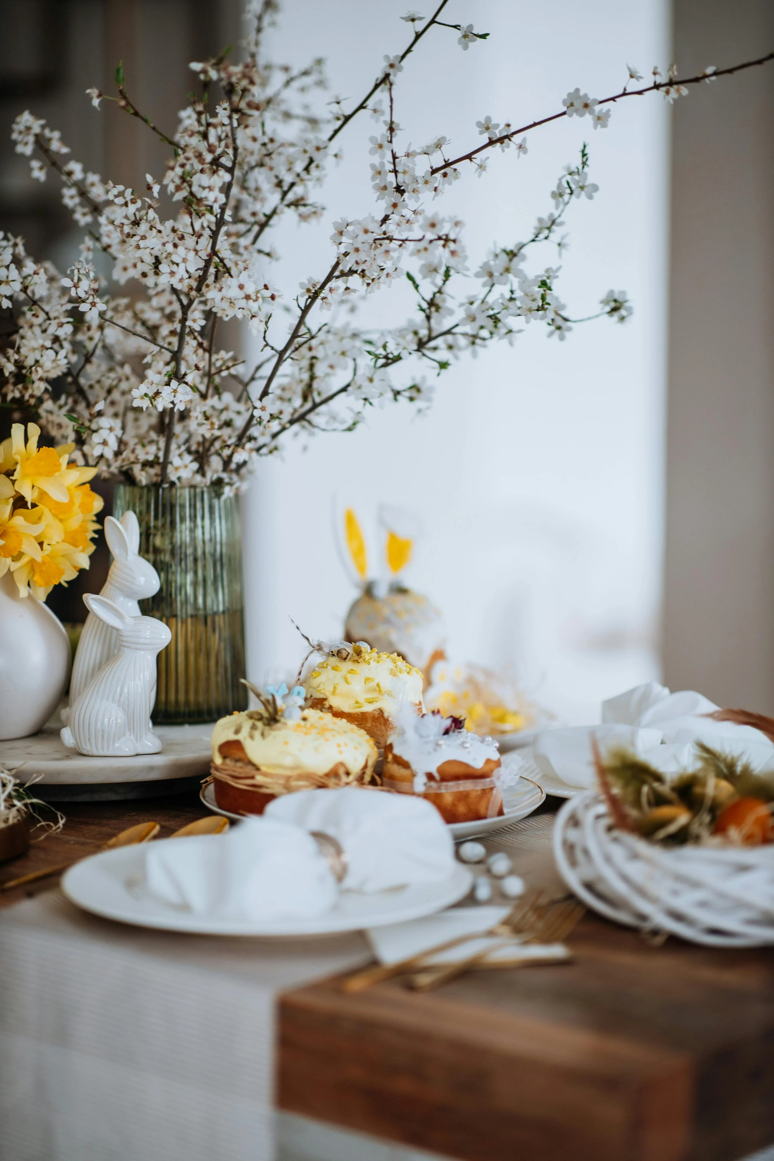 Table festive de Pâques, avec des petits gâteaux aux couleurs pastel et des fleurs blanches