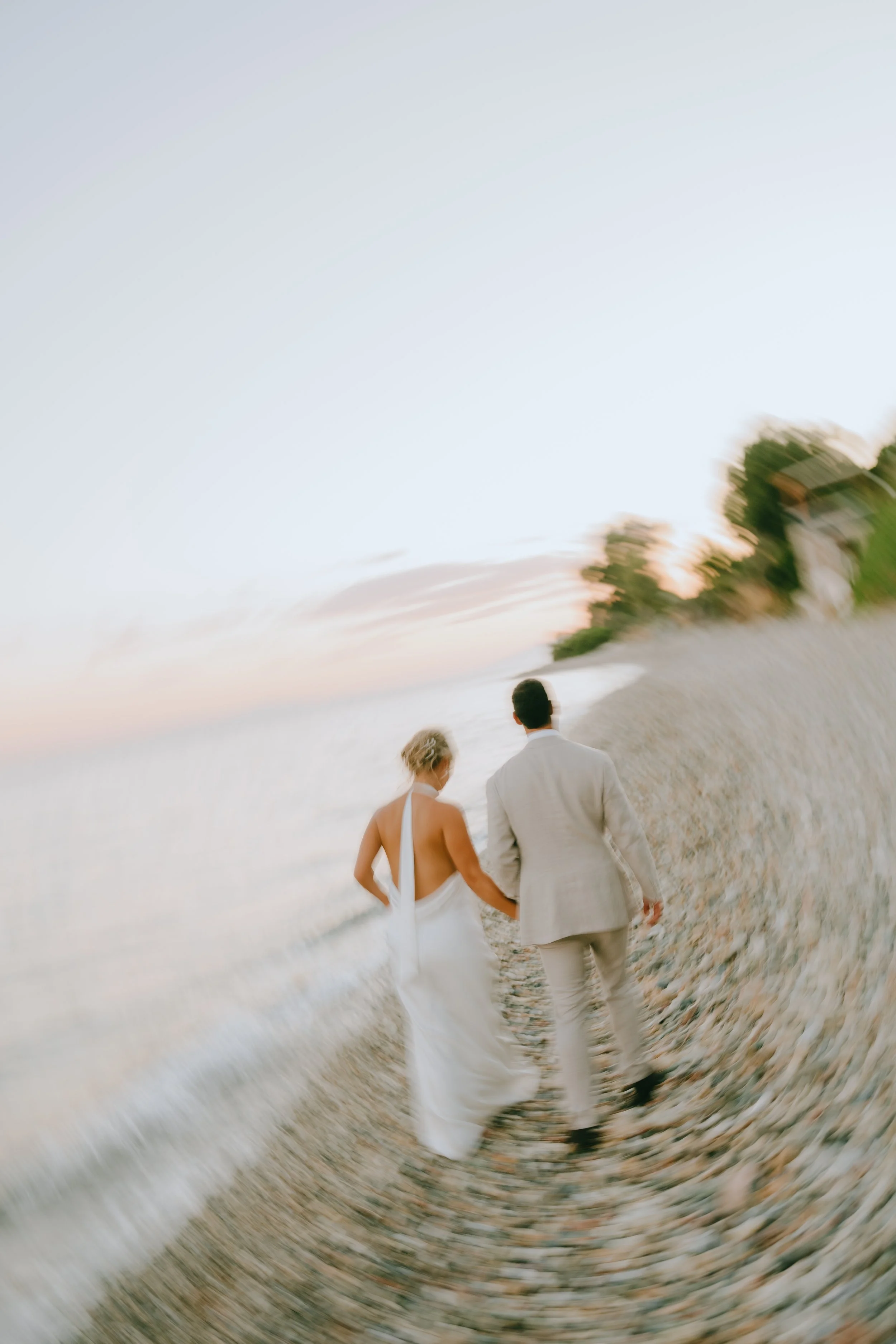 Couple walking hand in hand on a beach at sunset, with a slightly blurred and artistic effect.