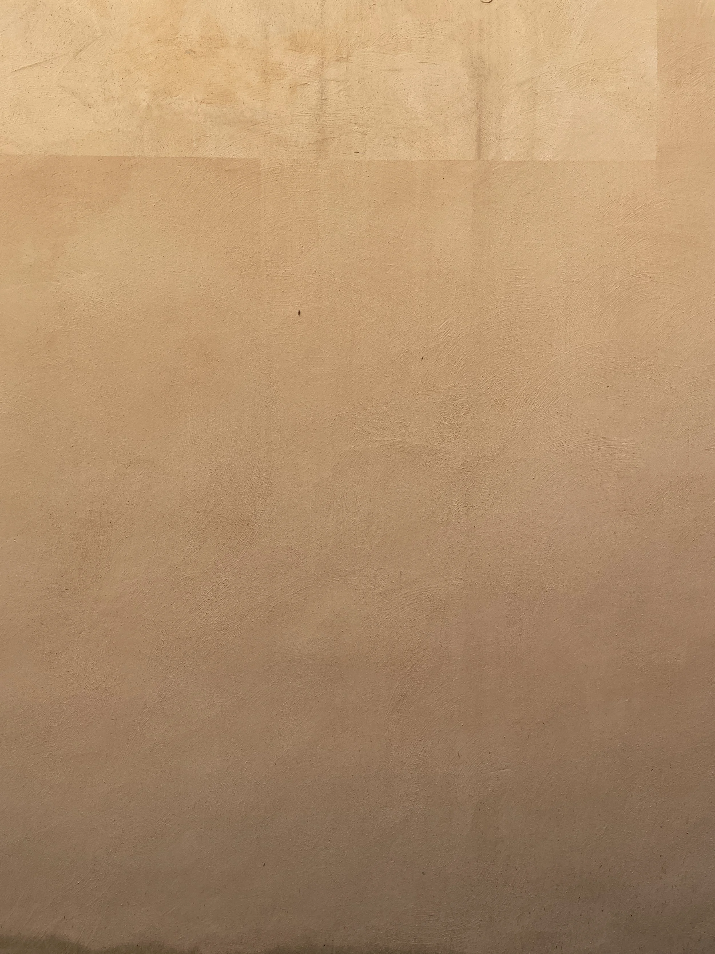 Close-up of a textured beige wall with some slight variations in color and tone.