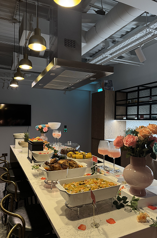 A buffet table with dishes, desserts, and floral arrangements in a modern dining area