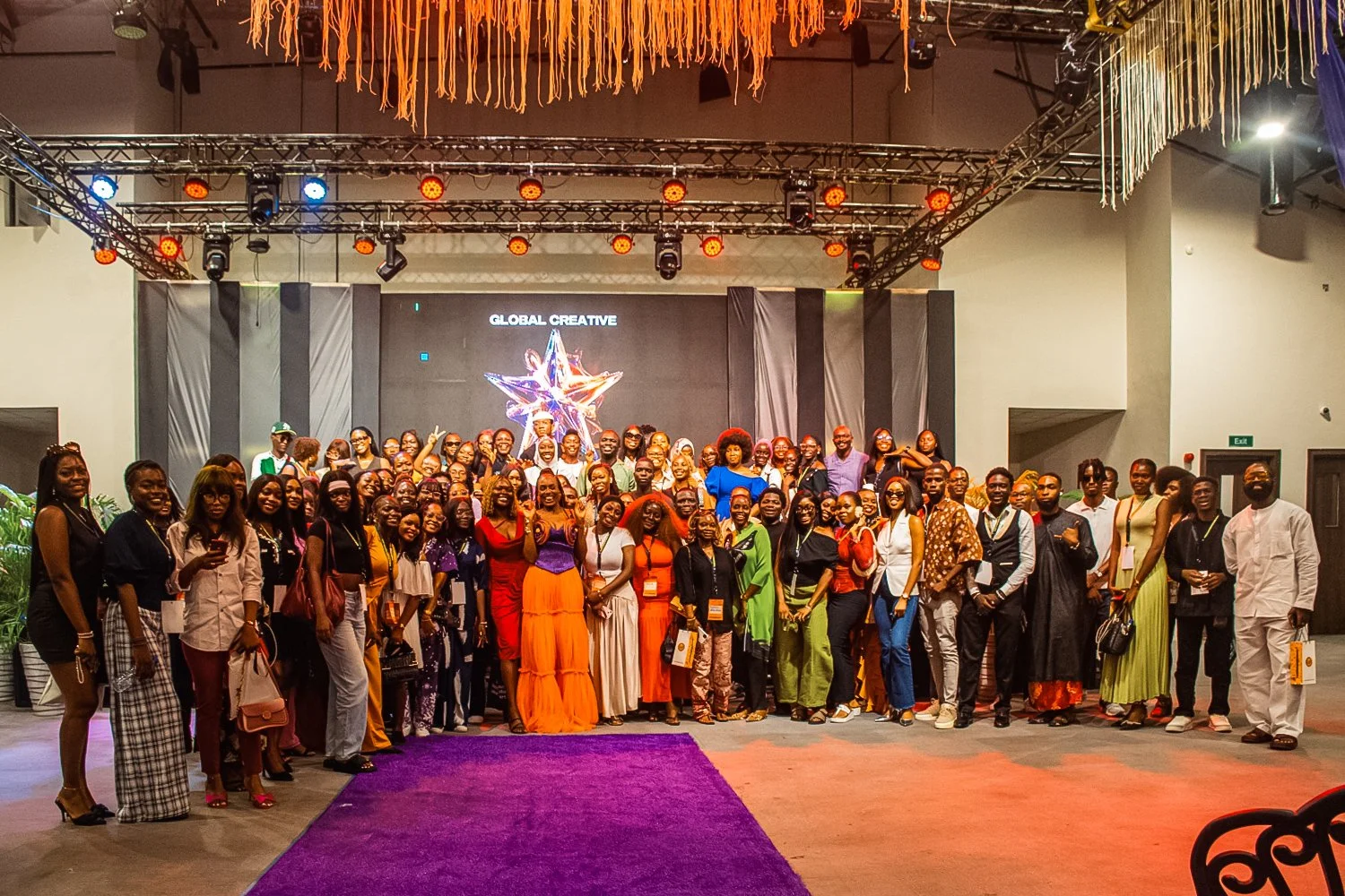 A large group of people on a stage at a conference or event, with a backdrop displaying the words 'Global Creative' and a colorful star logo.