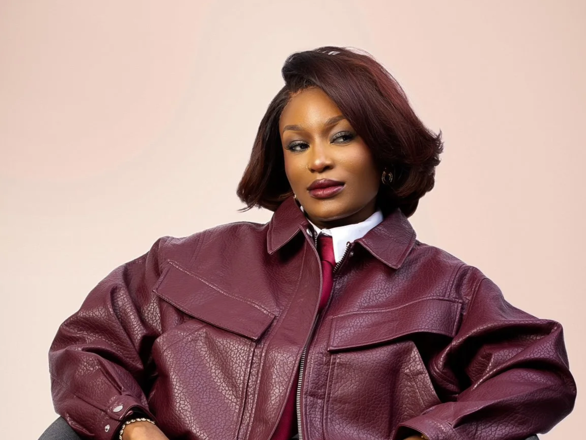 Mitchelle Chibundu with styled hair wearing a maroon leather jacket and white shirt against a neutral background.