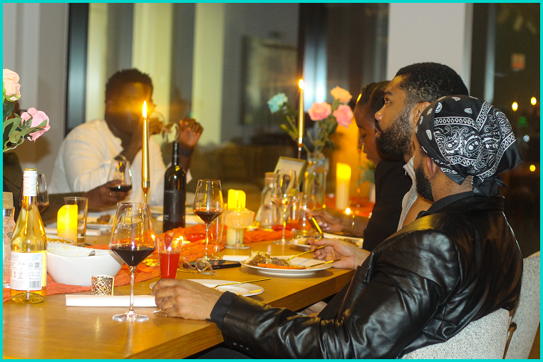 Group of friends enjoying a dinner party in a warmly lit restaurant, with candles and flowers on the table.