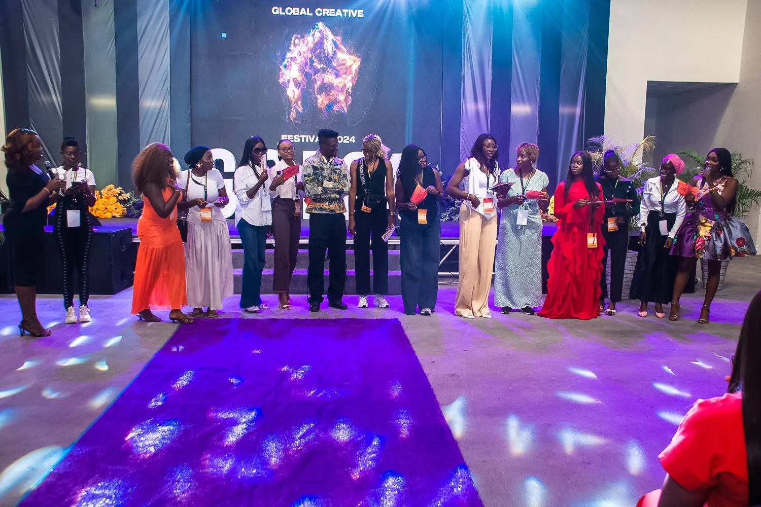 Group of diverse women standing on stage at an event, with a large LED screen behind them displaying 'Global Creative' and 'Festival 2024'.