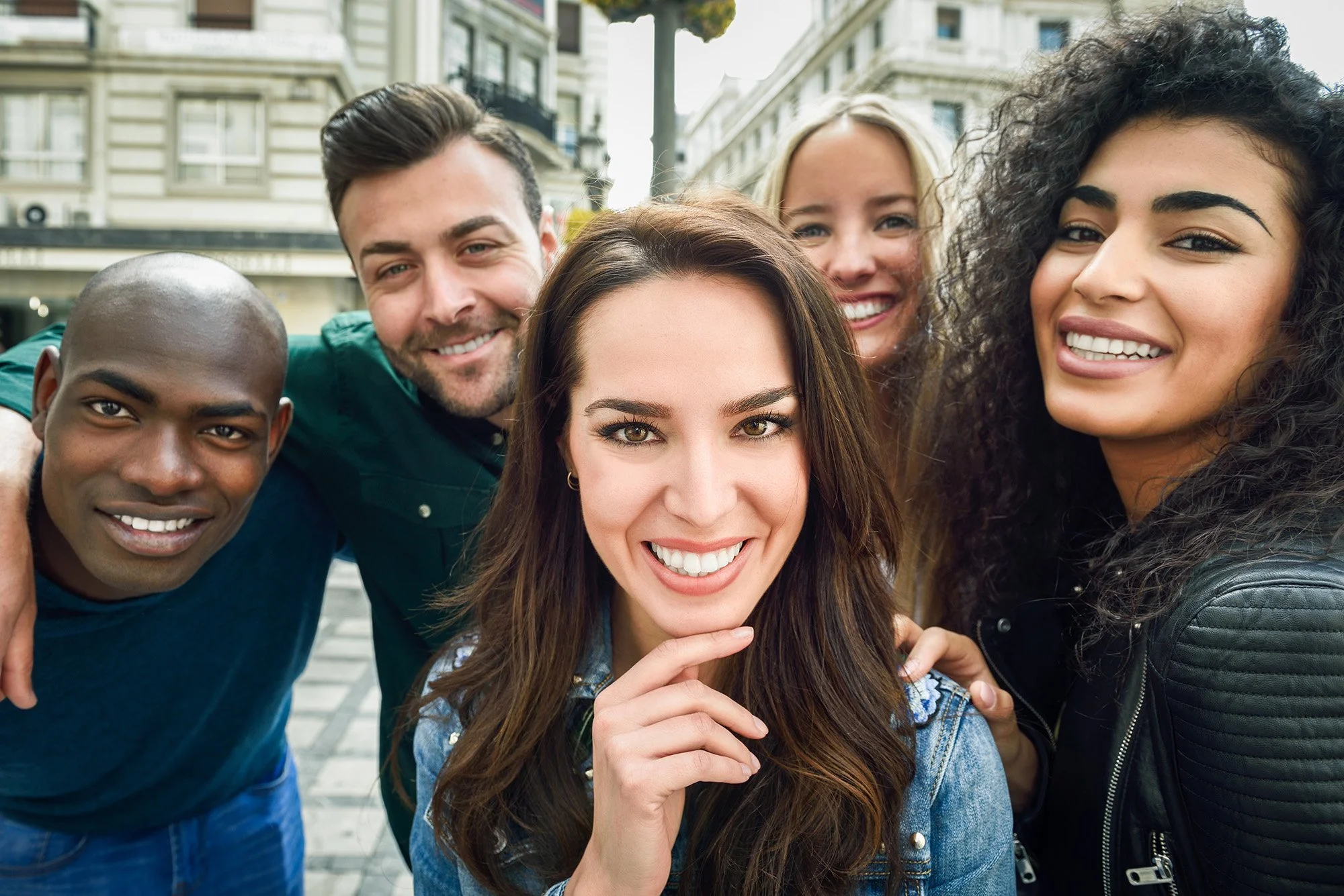 Five adults huddled and smiling at the camera