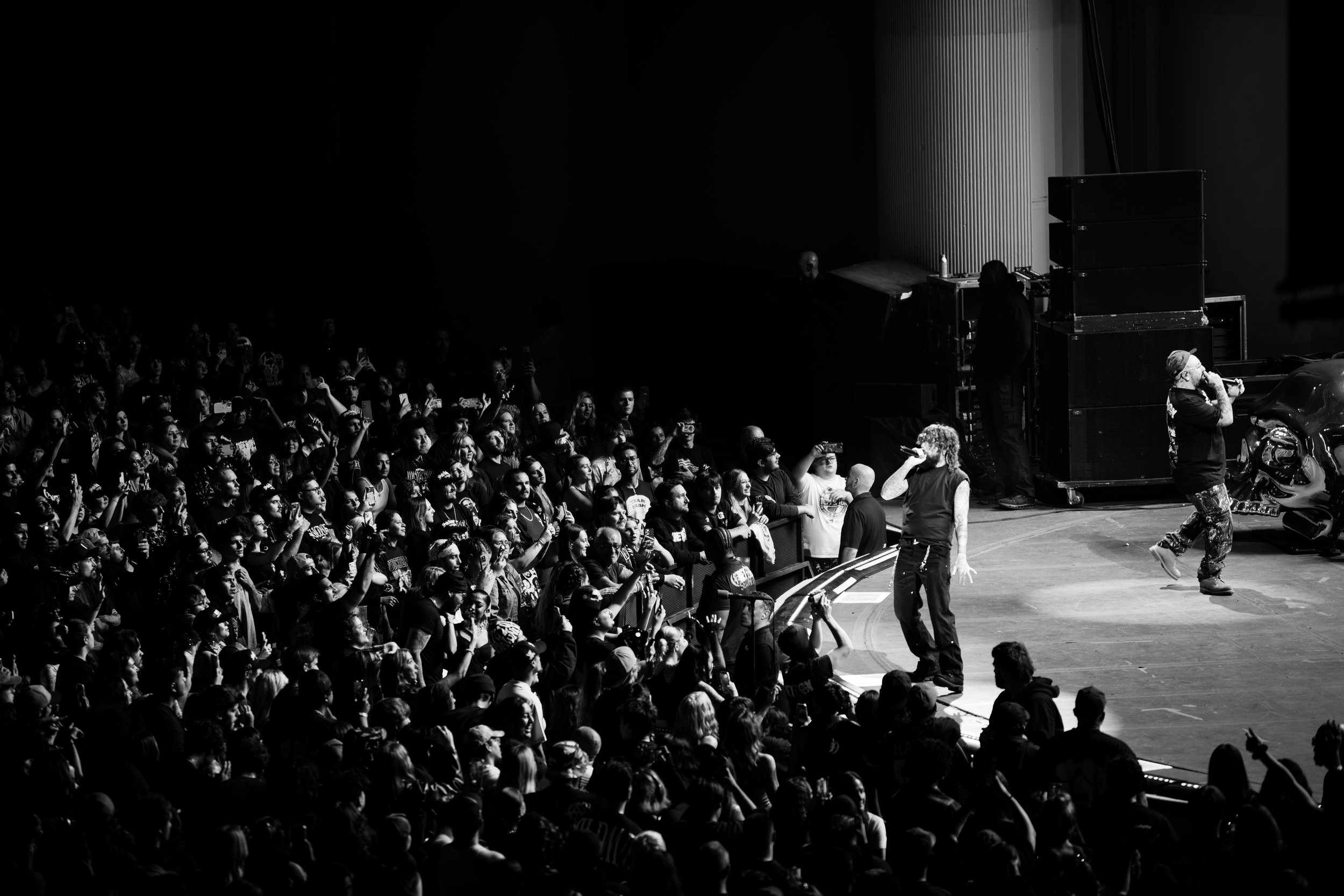 EDDY BAKER, BONES, LIVE NATION, CONCERT PHOTOGRAPHY, $UICIDE BOY$, Black and white photo of a concert stage with performers singing into microphones and a large audience watching and recording the performance.