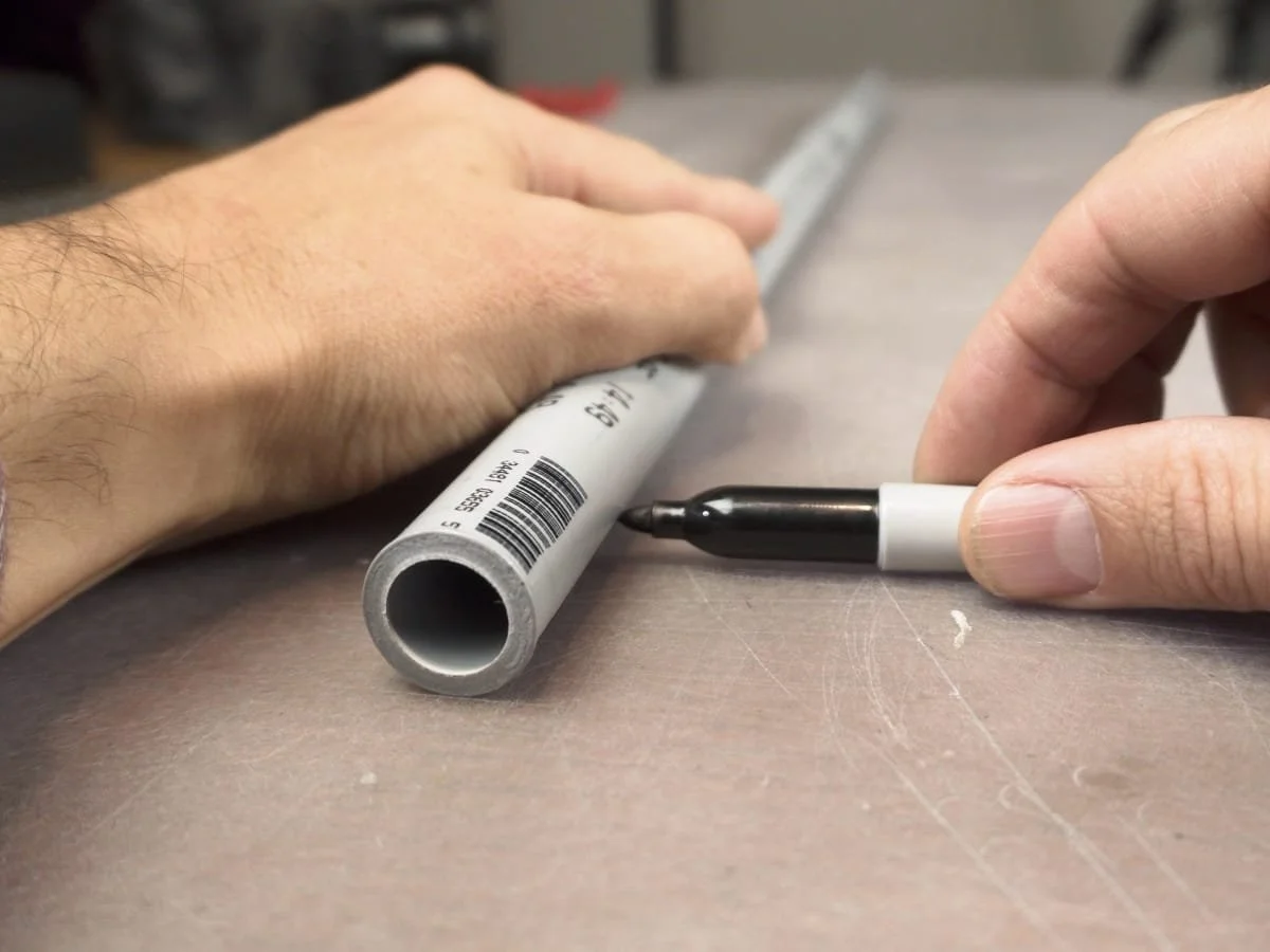 using a marker to mark line straight down the side of the pipe