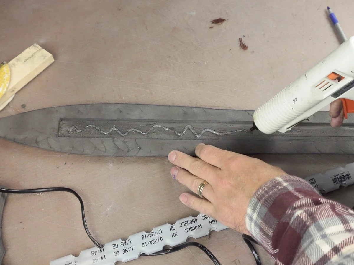 applying hot glue in the cutout on the blade
