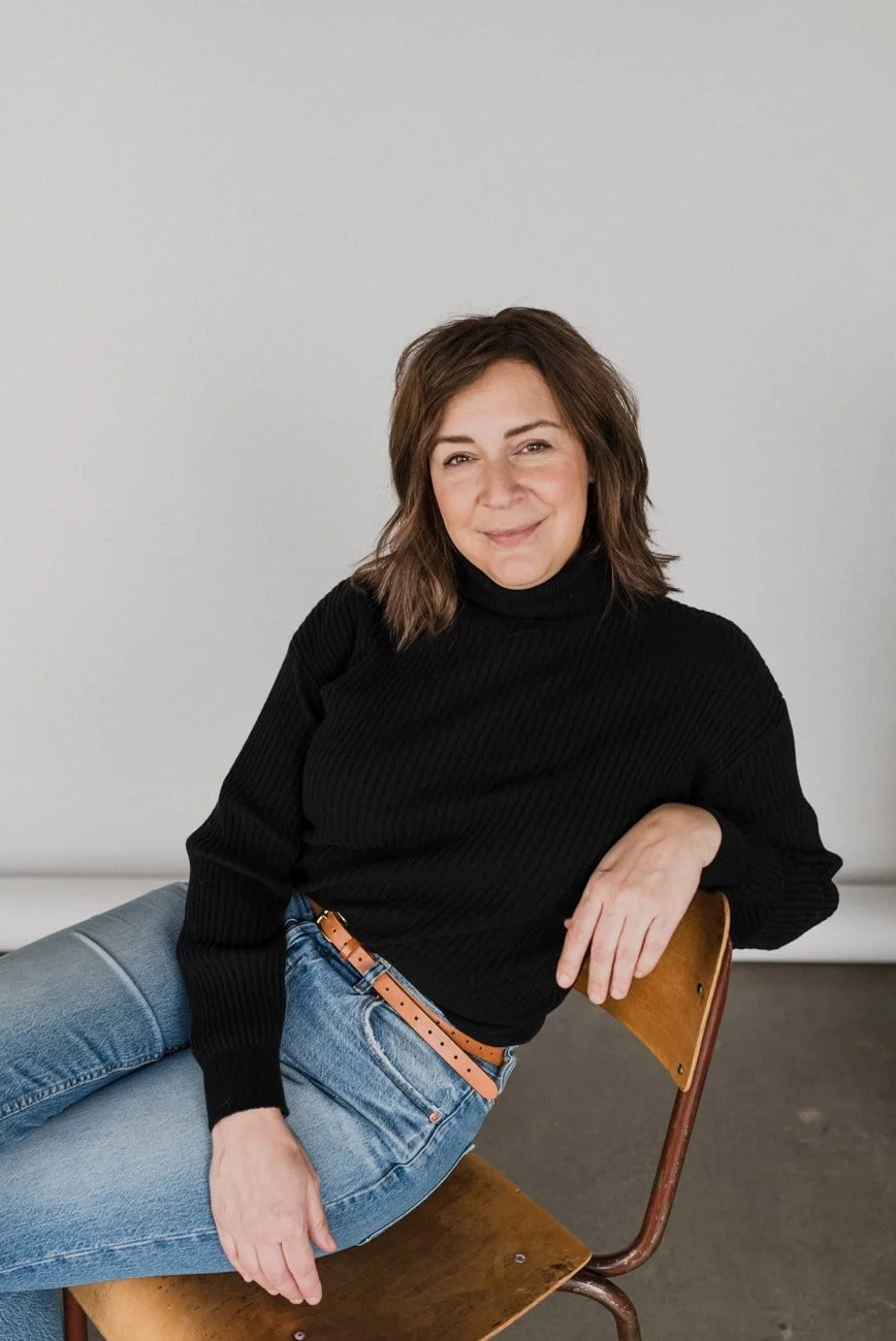 Sharla Bowker sitting on chair wearing blue jeans and black sweater in Vancouver.