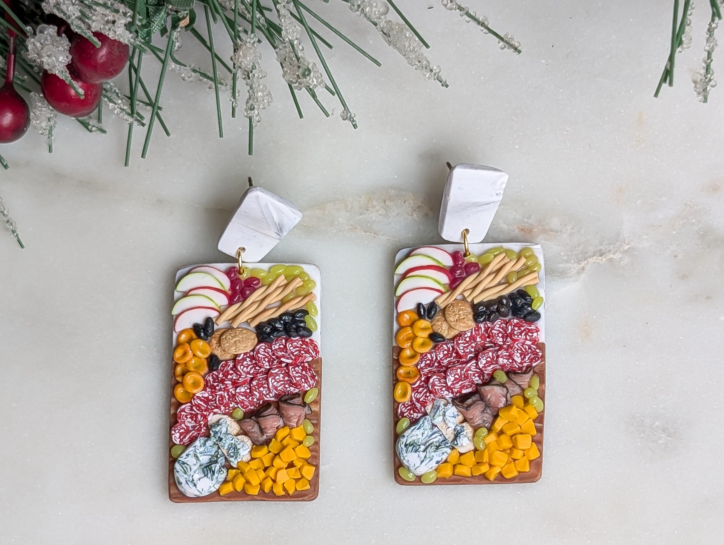 Handmade polymer clay earrings featuring marble and wood-like charcuterie boards adorned with realistic miniature food.