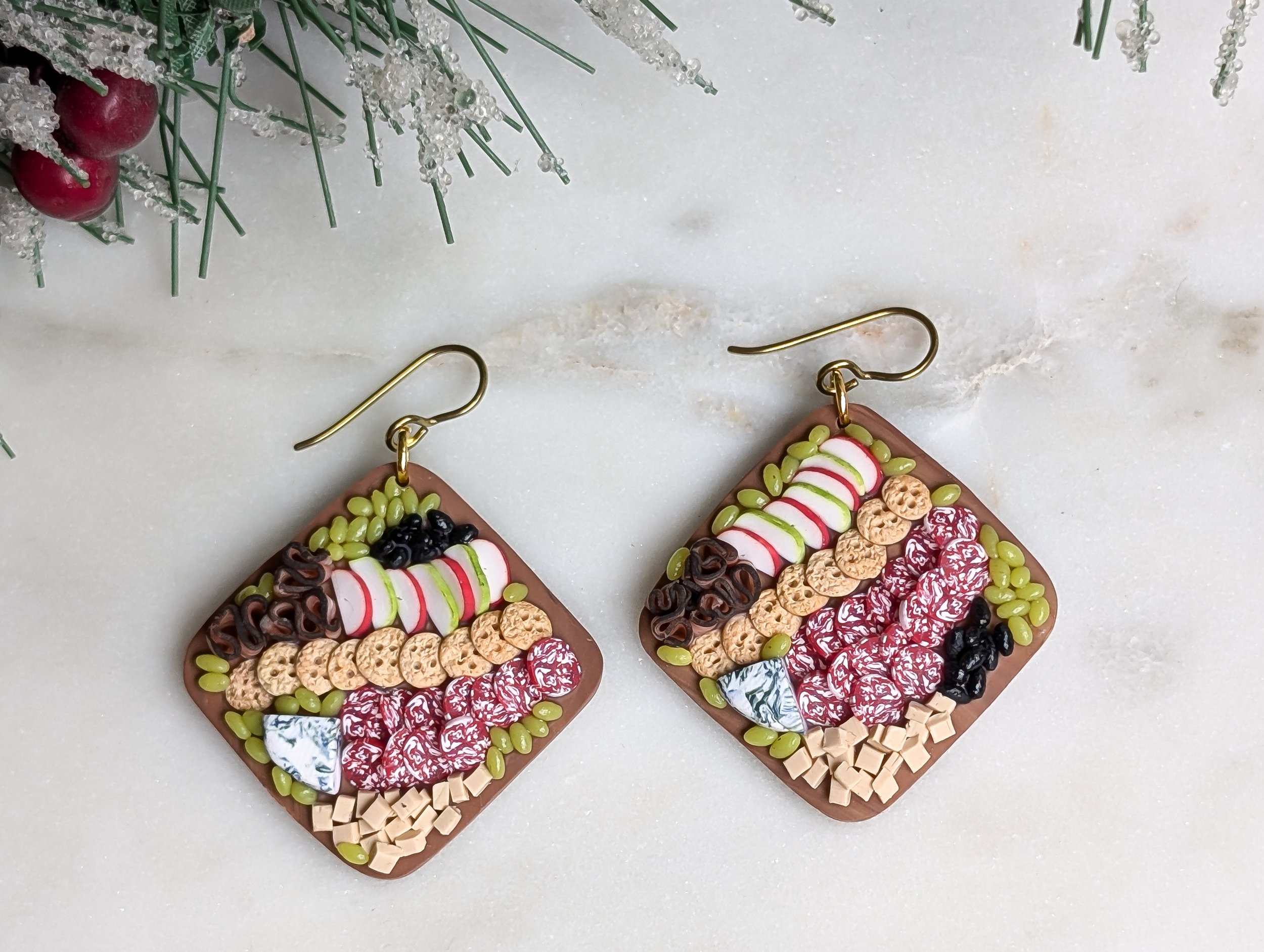Handmade polymer clay earrings featuring round wood-like charcuterie boards adorned with realistic miniature food.