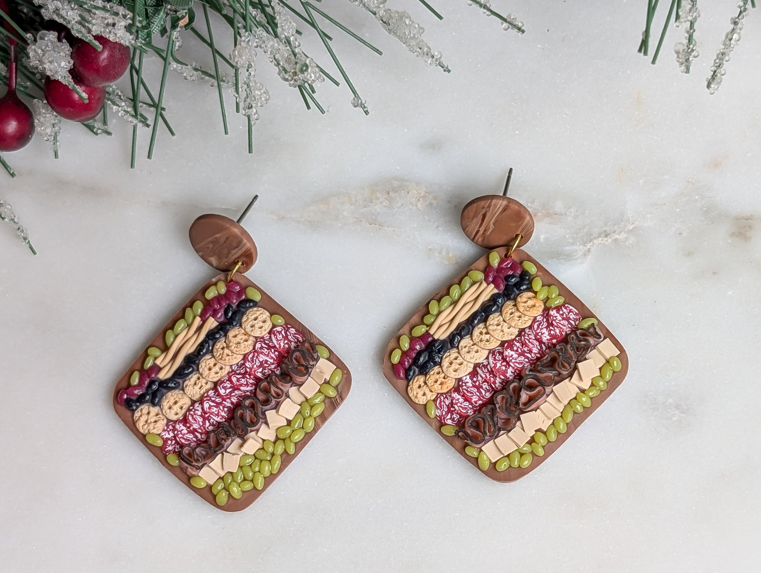Handmade polymer clay earrings featuring round wood-like charcuterie boards adorned with realistic miniature food.