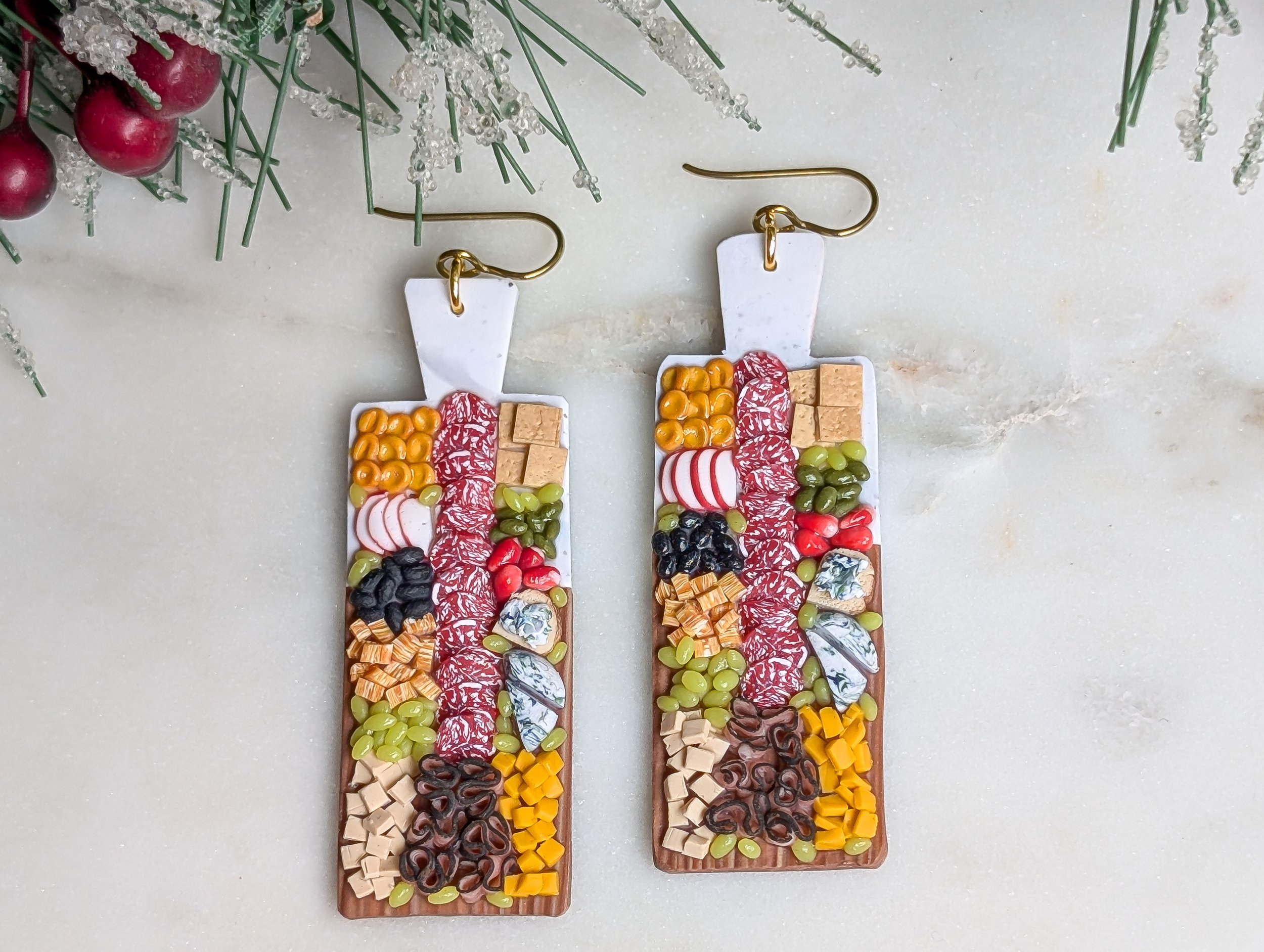 Handmade polymer clay earrings featuring marble and wood-like charcuterie boards adorned with realistic miniature food.