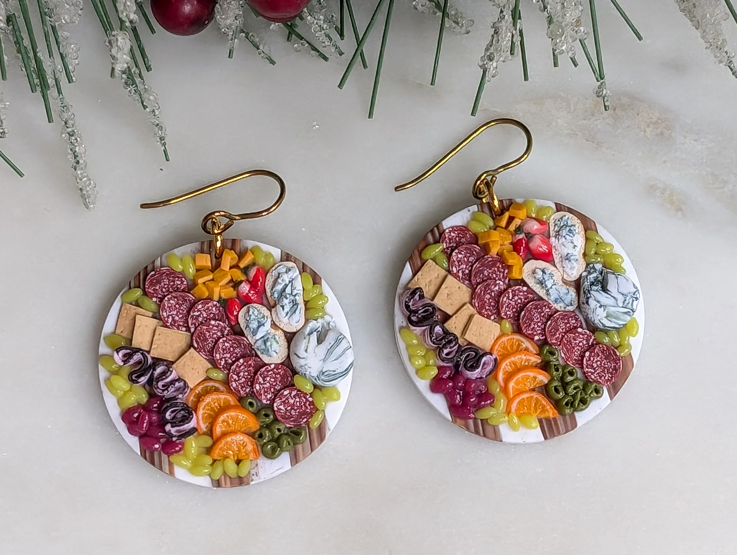 Handmade polymer clay earrings featuring marble and wood-like charcuterie boards adorned with realistic miniature food.