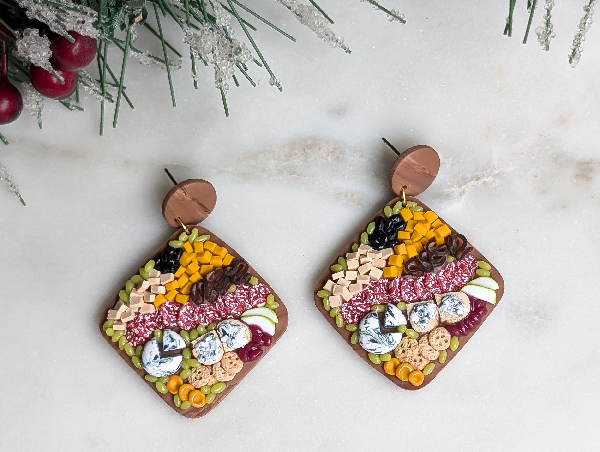 Handmade polymer clay earrings featuring round wood-like charcuterie boards adorned with realistic miniature food.