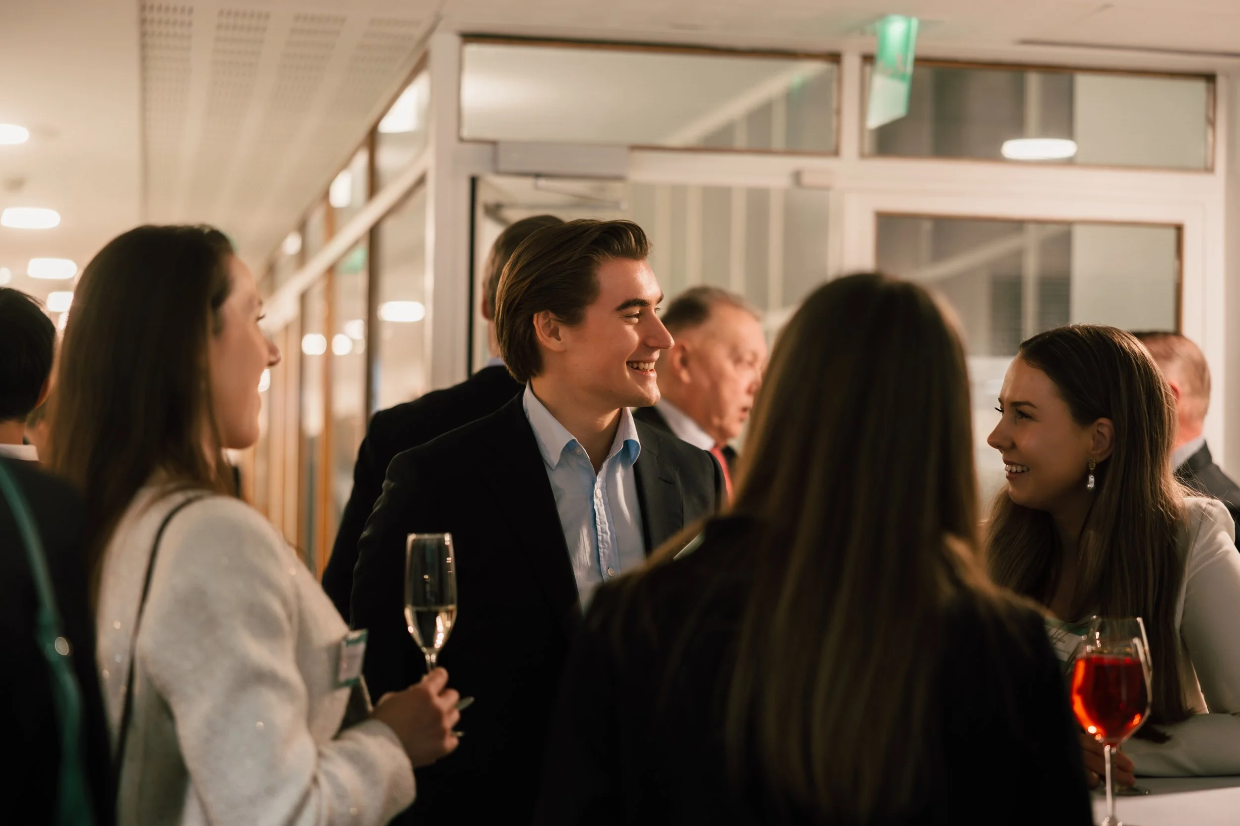 Corporate event networking in Helsinki – professionals smiling during an in-person business event, captured in a natural, candid style by a Helsinki corporate event photographer, highlighting authentic connections, professional atmosphere, and real i
