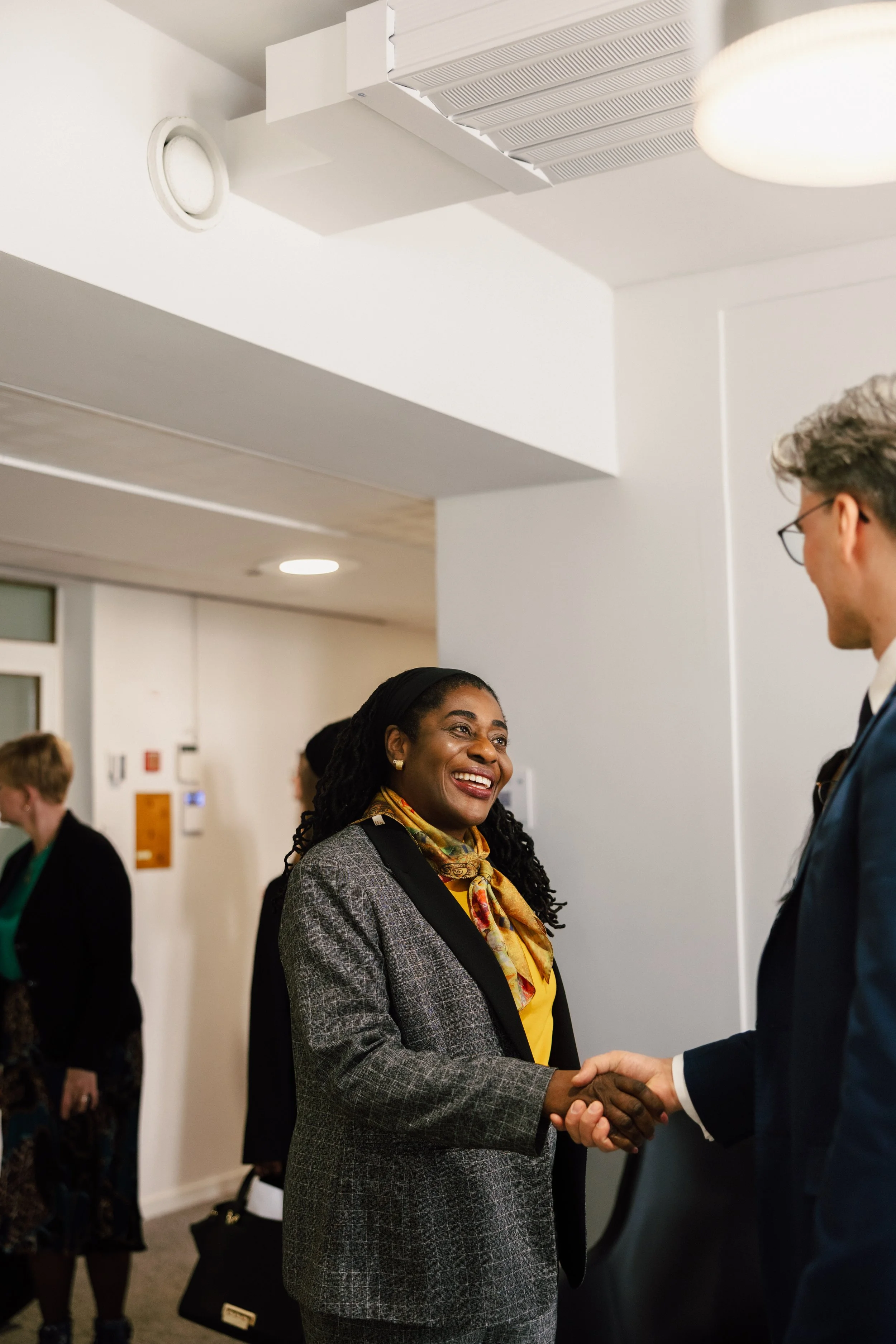 Corporate event networking in Helsinki – professionals shaking hands and smiling during an in-person business event, captured in a natural, candid style by a Helsinki corporate event photographer, highlighting authentic connections, professional atmo