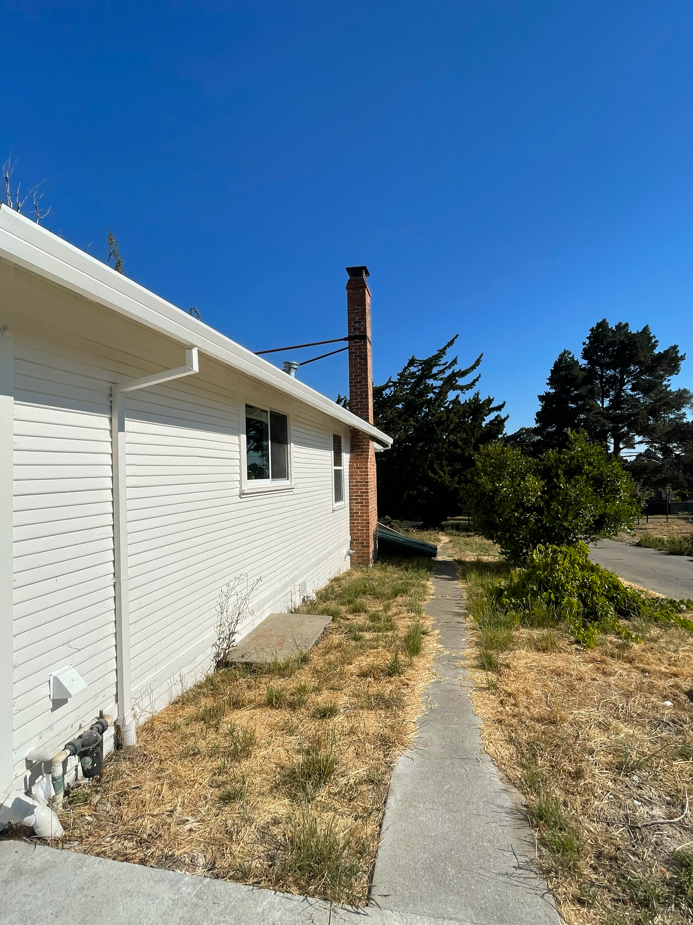 Before photo showing the kitchen window, existing pathway, and Lemon tree