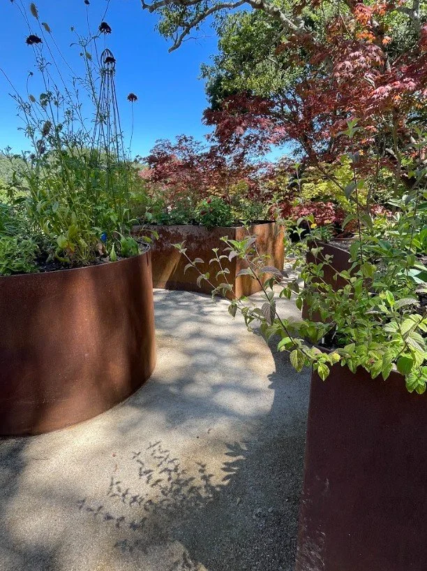 Custom corten steel raised beds designed in a keyhole pattern serve as a cut flower garden. Crafted and installed by Mike Solari