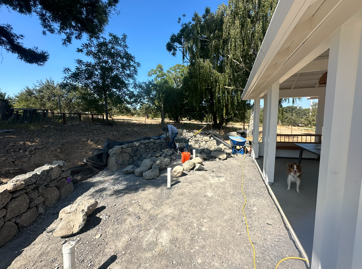 In progress photo of the stone wall, hearth, and patio with drainage