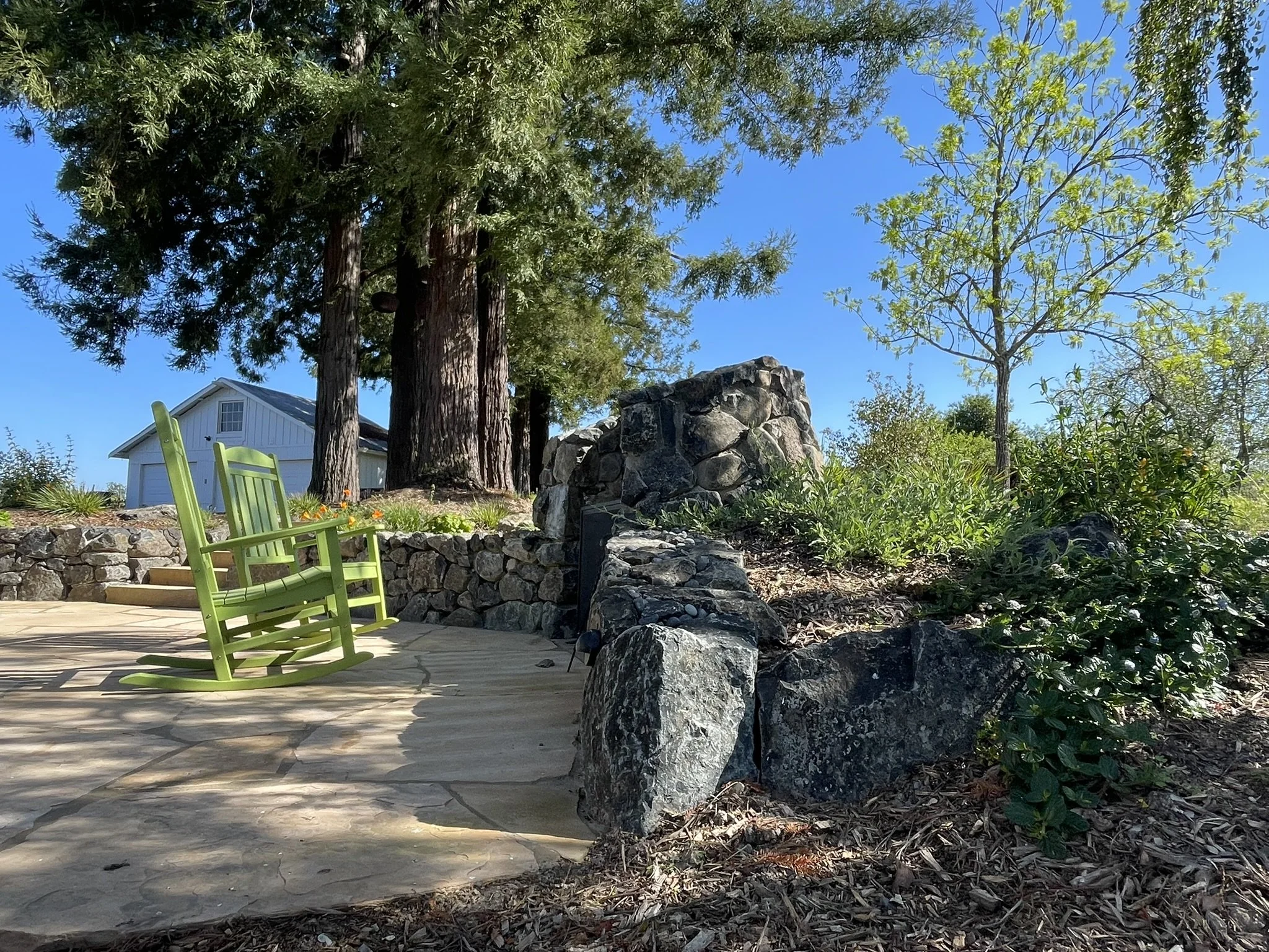 Two rocking chairs rest in front of the stone hearth on a new flagstone patio