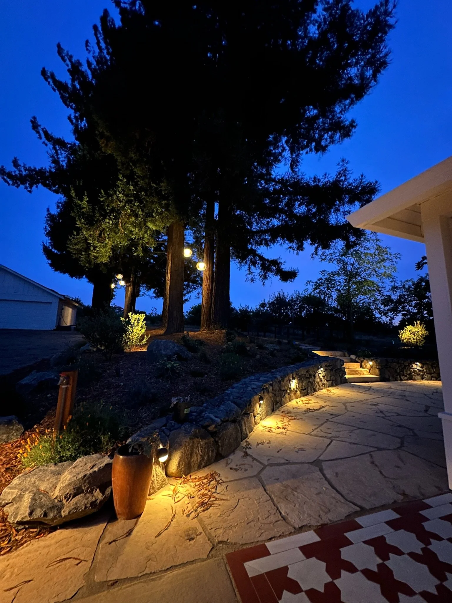 Flagstone patio and drystack stone wall pictured at night with low voltage landscape lighting