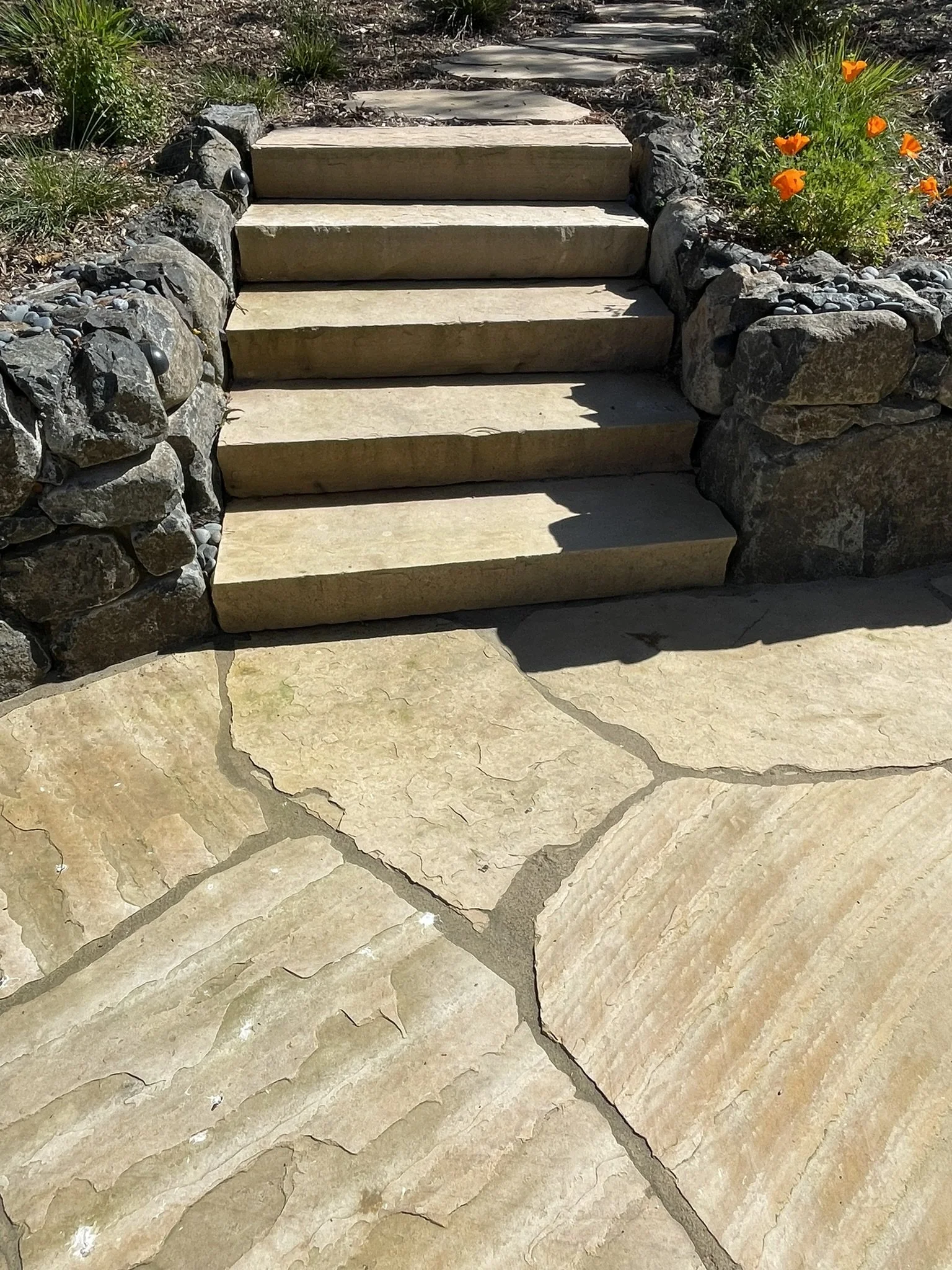 Stone slab steps lead from the patio to the veggie garden