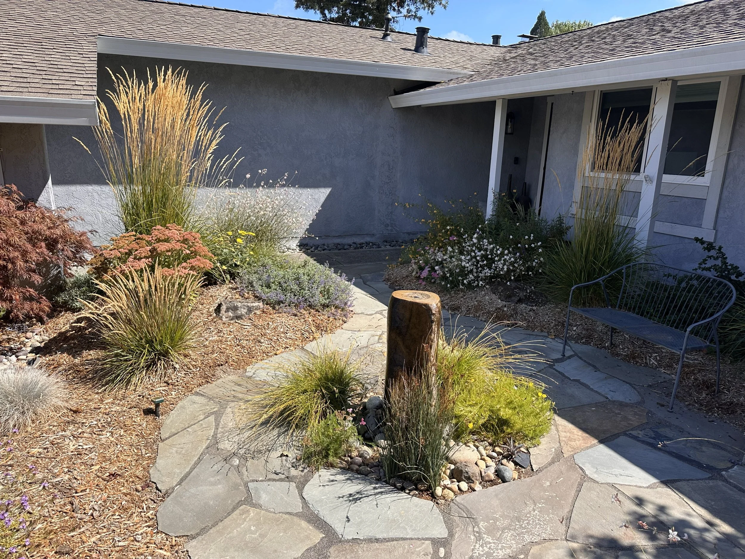 Dryset flagstone patio surrounding a recirculating boulder fountain.  Excavated soil from the patio is used to create planting berms