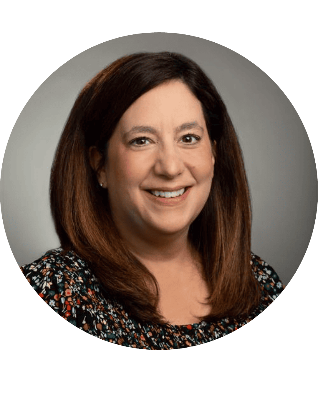 Headshot of a woman with shoulder-length brown hair, smiling, wearing a colorful floral top.