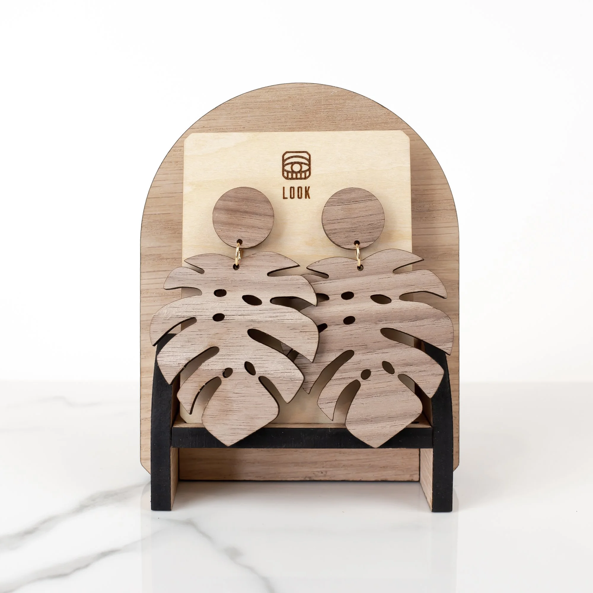 Image of handmade Angelie laser cut walnut wood dangle earrings displayed on a Look branded basswood earring card on a small front facing arch display.