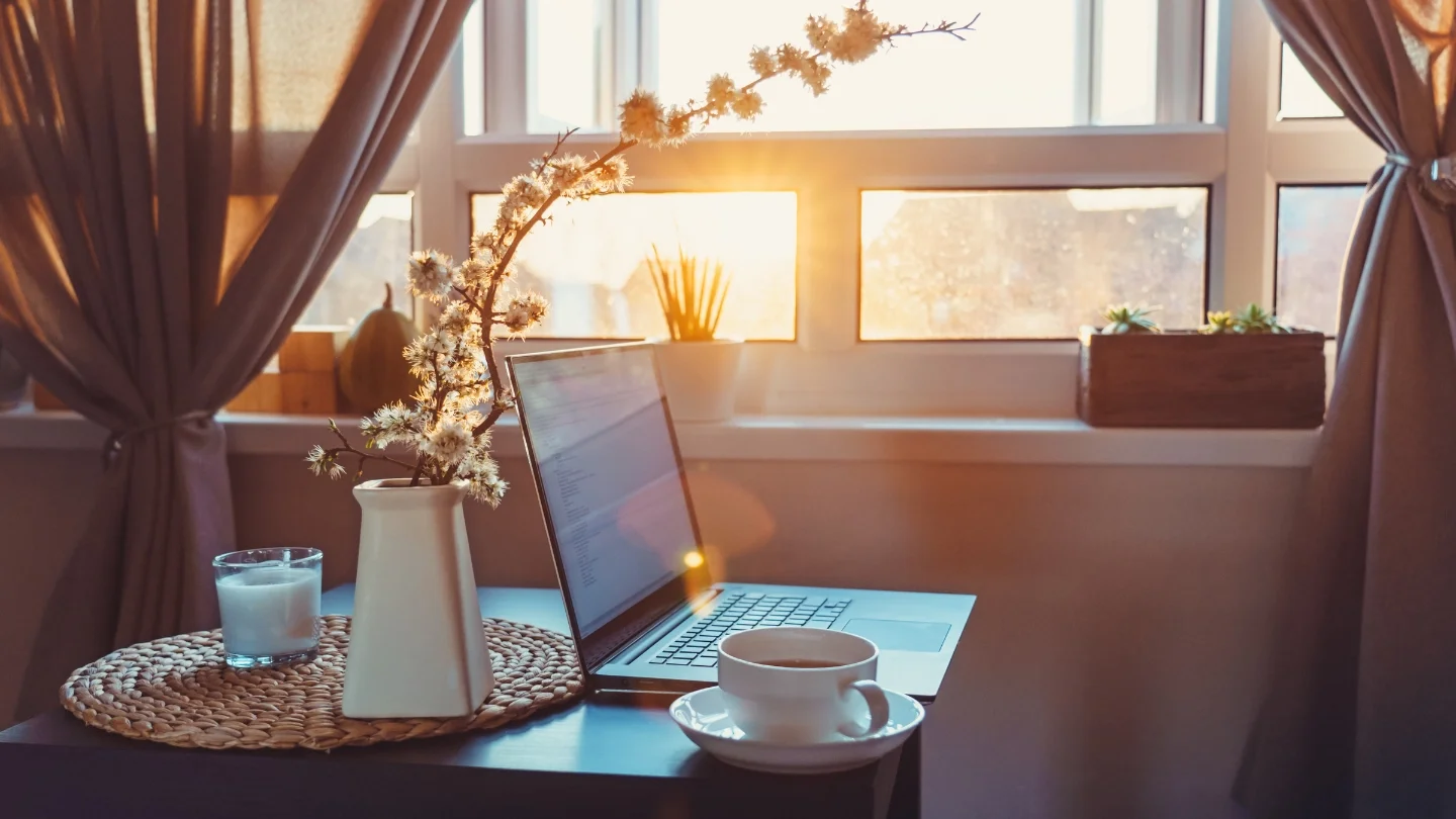 Laptop and coffee by a sunlit window, representing the Friendly Circle YouTube video library and online resources.