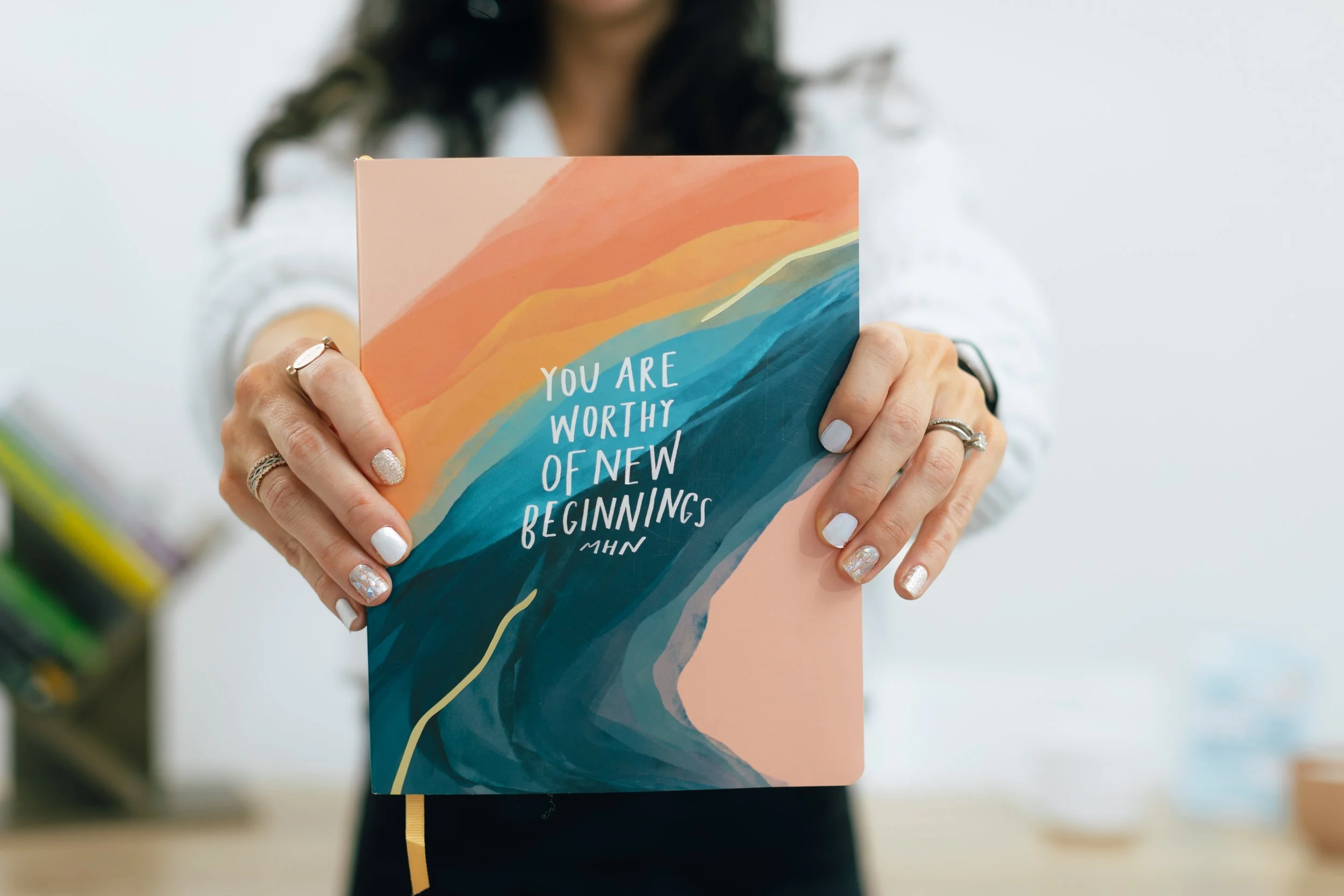 Dr. Chrissy Chard in her home in Denver holding notebook with quote, "you are worthy of new beginnings." Ties to theme of framing midlife and perimenopause as transformation.