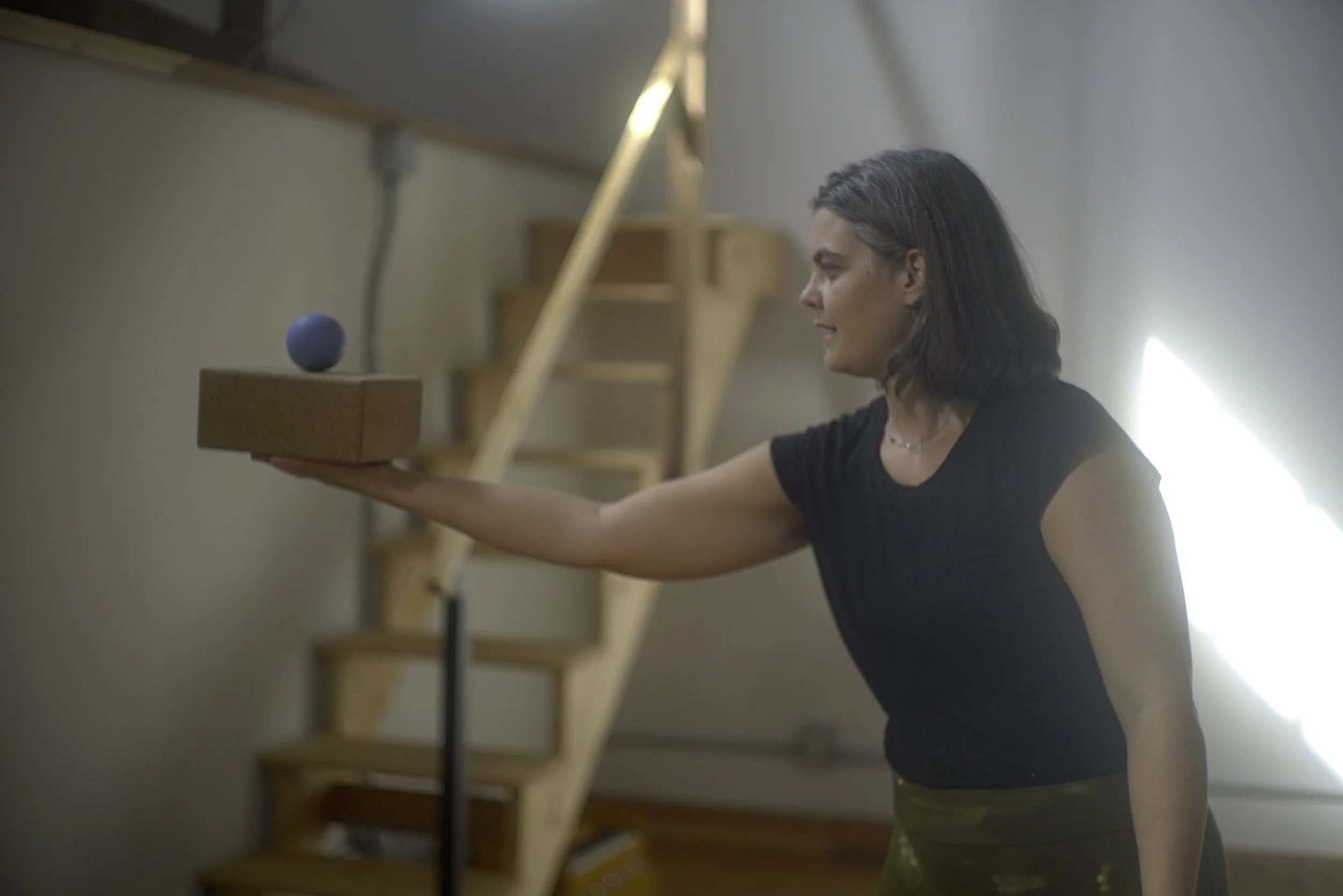 Willa holds her arm out, balancing a ball on top of a yoga block