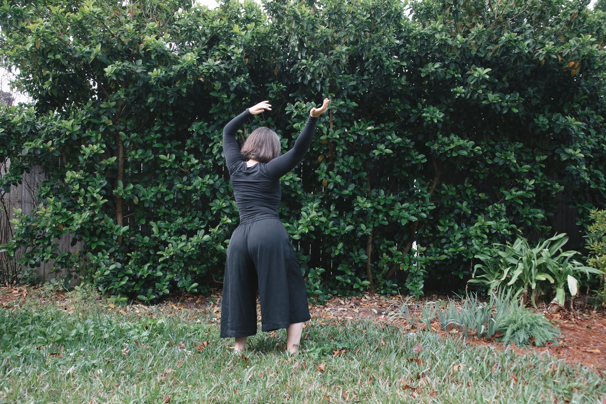 Willa dances in the grass of her backyard, wearing long black pants and a black long sleeve shirt.