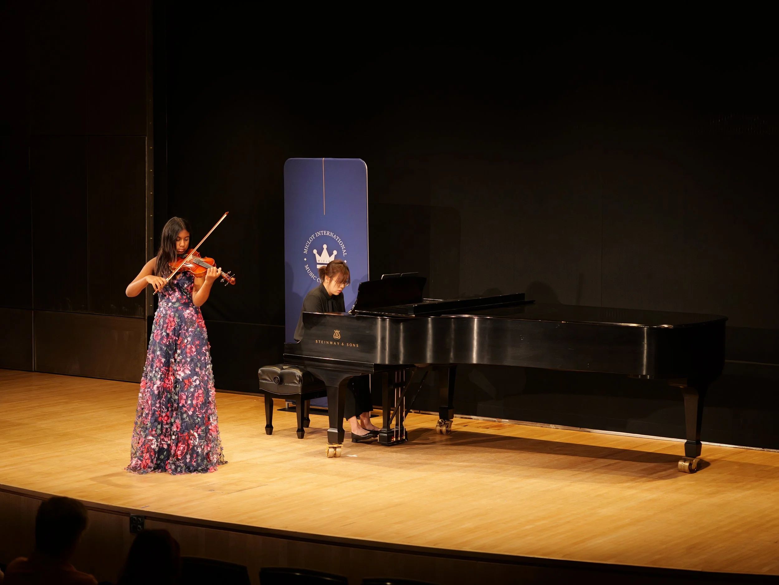 Musician playing violin on stage with ocean view in background