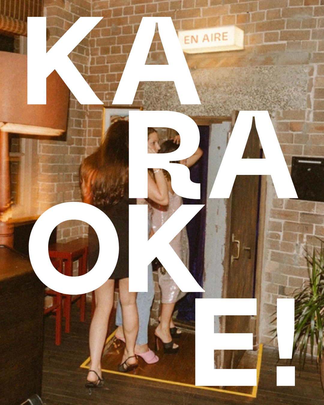 People in a dressing room trying on shoes, with a large white text overlay that says 'KARA OK!' and a sign above that says 'EN AIRE', in a brick-walled room.