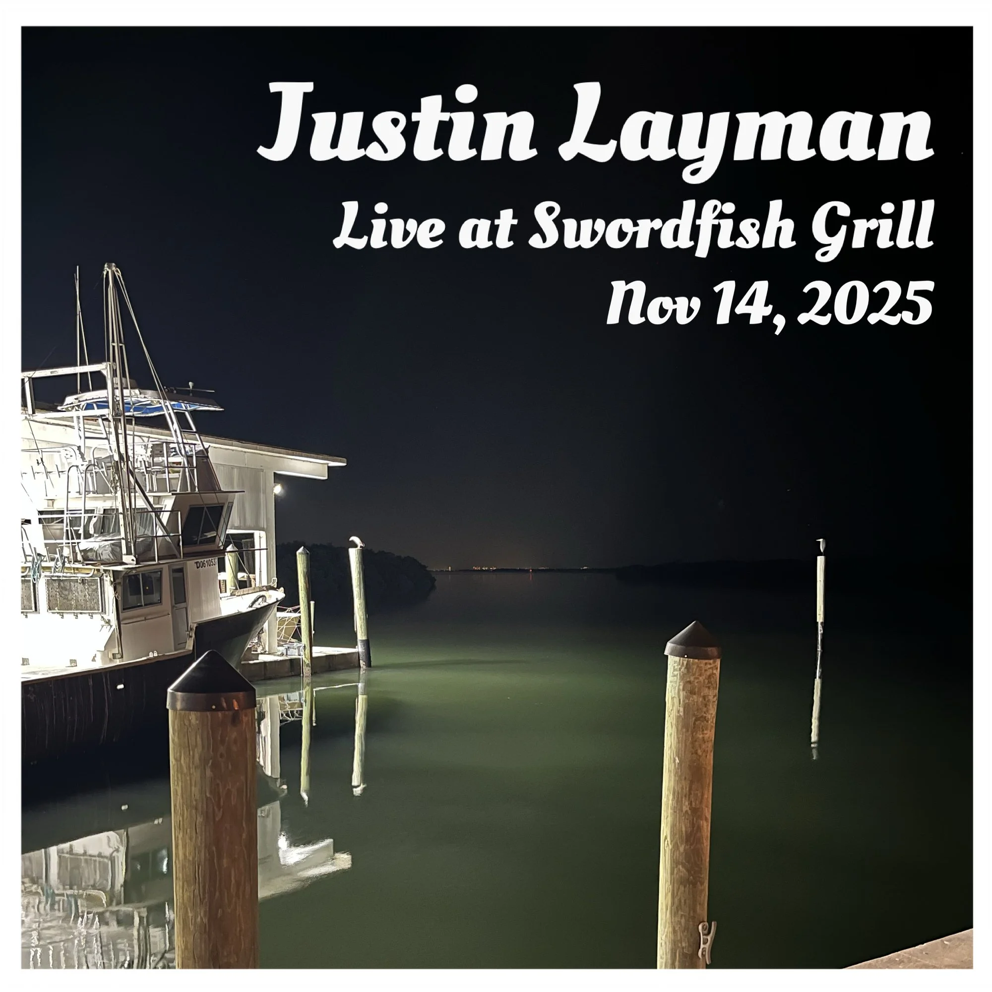 Nighttime view of boats docked at a marina on calm water, with wooden posts in the foreground and dark sky in the background, advertising a Justin Layman live event at Swordfish Grill on November 14, 2025.