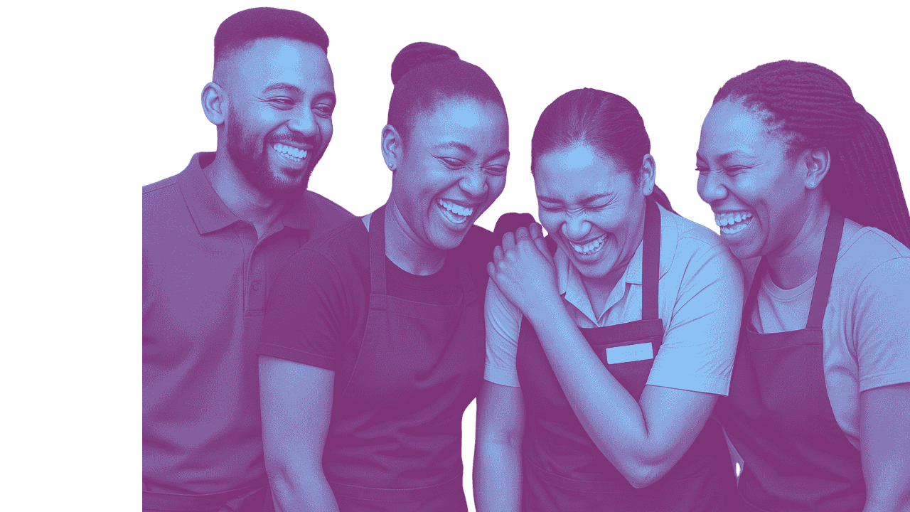 Four people, two men and two women, laughing together and wearing work aprons