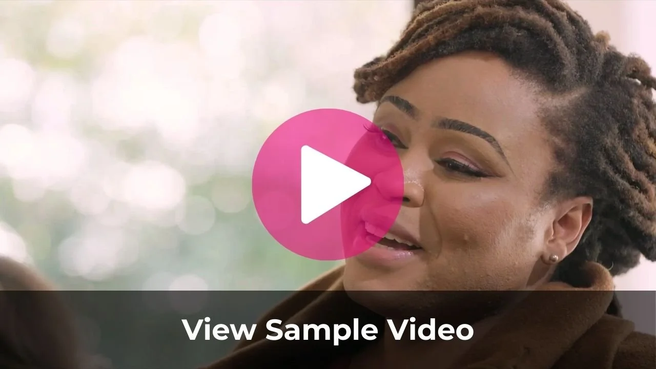 A woman with styled dreadlocks smiling while talking, with a pink play button icon in the center and text that says "View Sample Video" at the bottom.