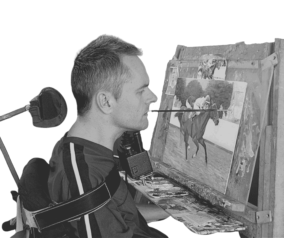 An artist in a wheelchair paints a horse race on an easel, with a paintbrush held in his mouth, while wearing a mask.