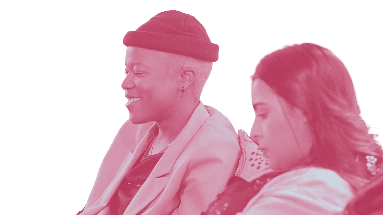 Two women sitting side by side, smiling and with eyes closed, one wearing a beanie hat and the other with long hair, colored in pink.