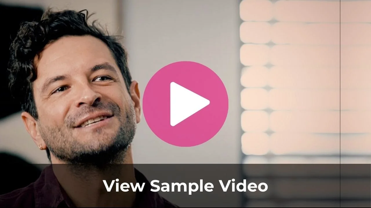 A man with dark, wavy hair and a beard smiling, with a pink play button overlay and the text "View Sample Video" at the bottom.