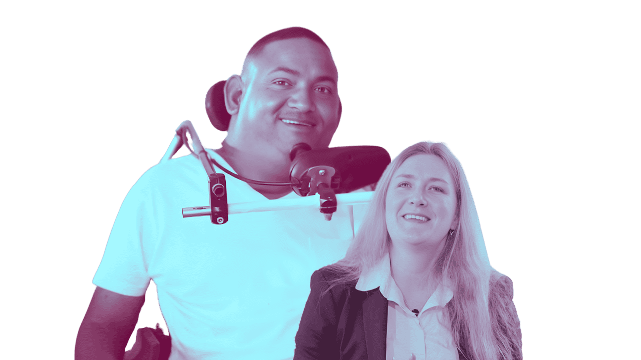 A man in a white shirt in a wheelchair smiling and a woman with long blonde hair smiling beside him, against a black background.