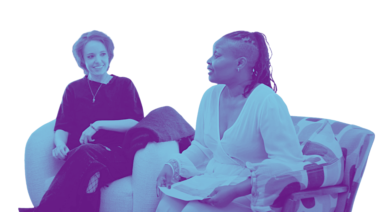 Two women having a conversation on couches in a relaxed setting.