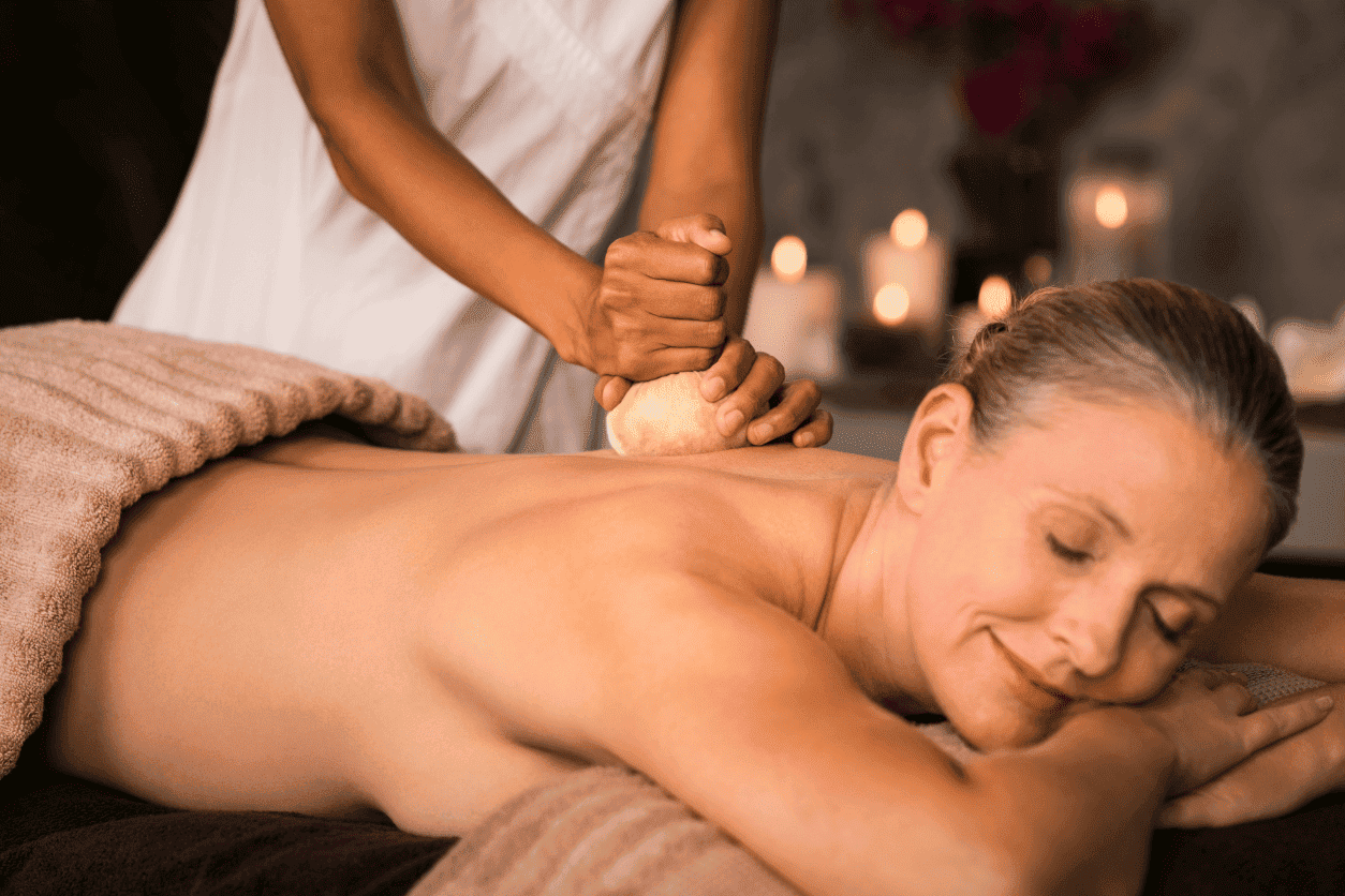 A person receiving a back massage in a dimly lit room with candles.