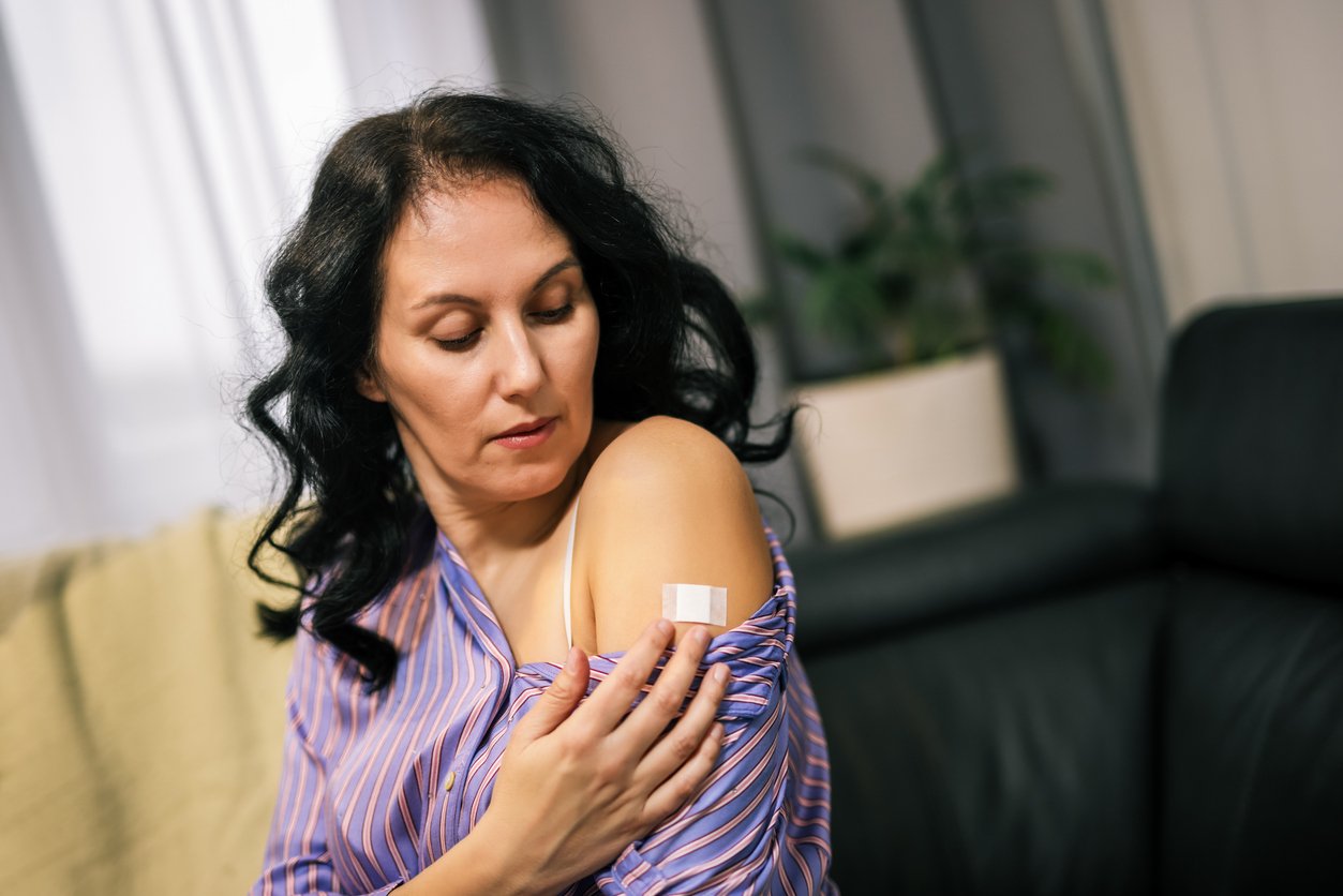 Woman applying menopause hormone therapy patch