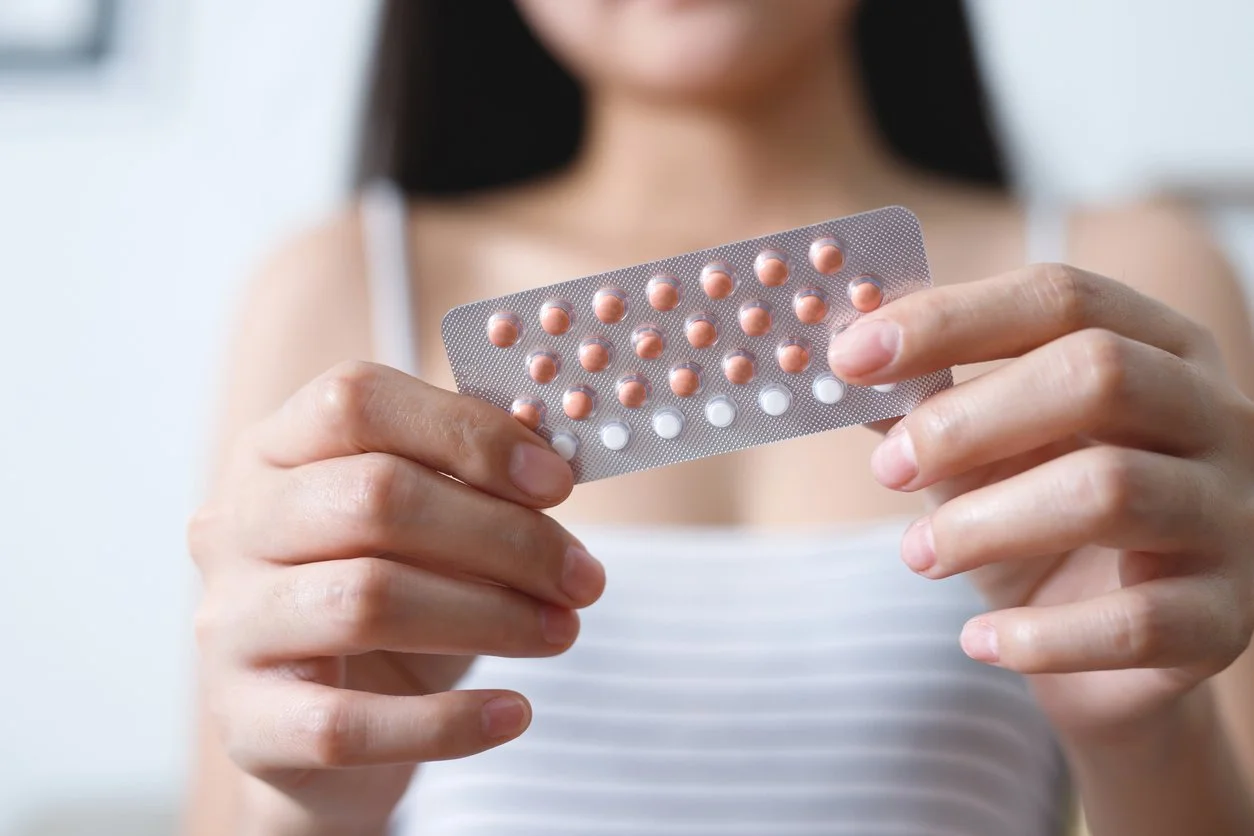 A woman holding a pack of birth control pills